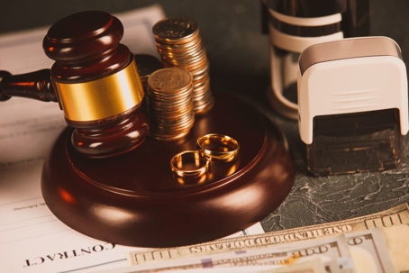 Gavel next to stack of money and wedding bands